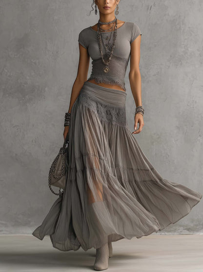 Set composto da top grigio trasparente con pannelli in pizzo e gonna maxi plissettata