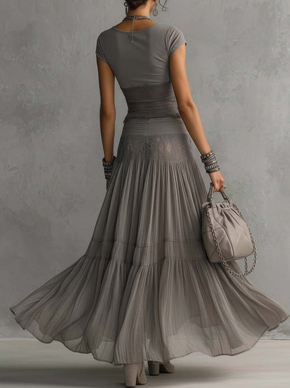 Set composto da top grigio trasparente con pannelli in pizzo e gonna maxi plissettata